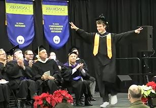毕业的学生走向讲台，双臂张开庆祝